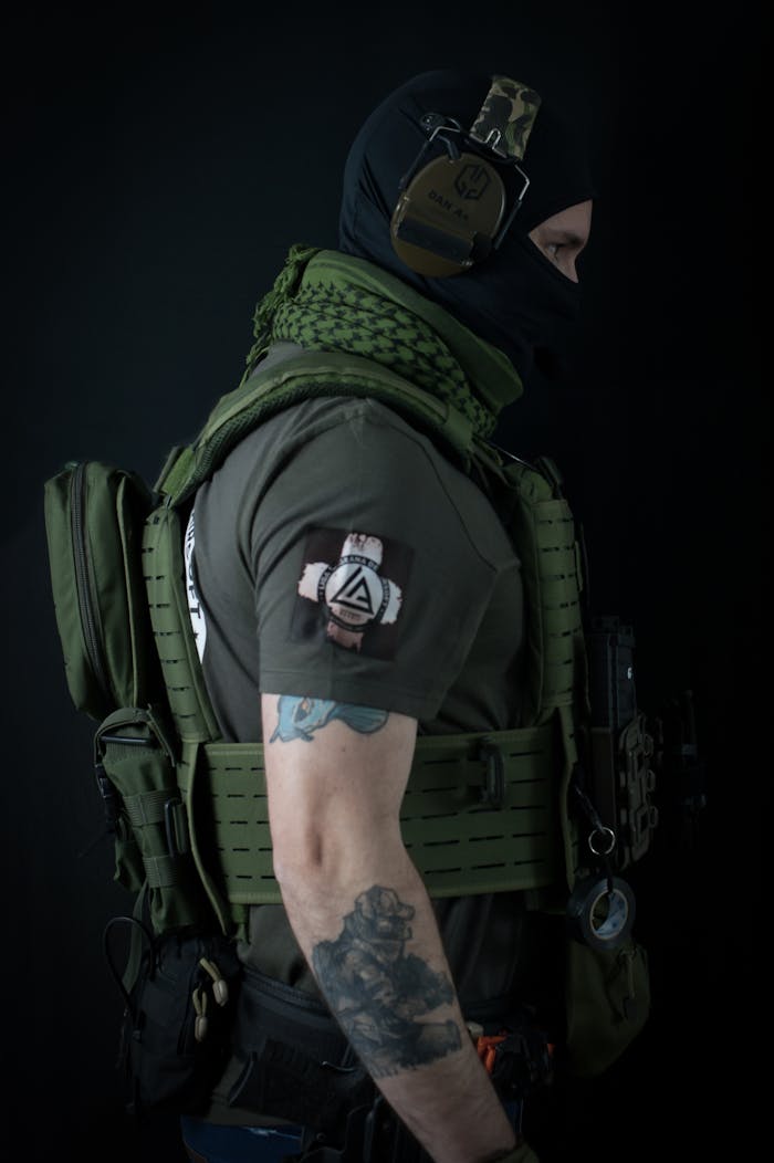 A heavily tattooed soldier in tactical gear and uniform, prepared for action.